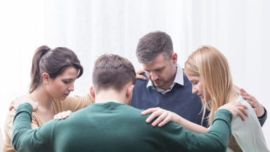 Small group praying in circle with hands on shoulders