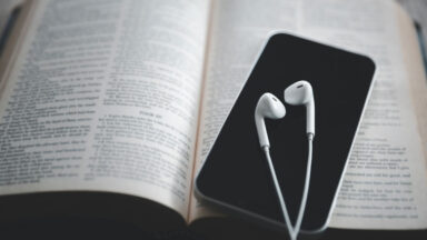 iphone user listening to Christian podcast and reading bible