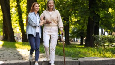 mom with MS walking with a cane and her daughter