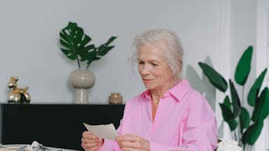 Elderly woman enjoying memories through old photographs, indoors setting.