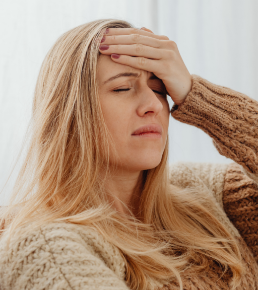 Woman holding her forehead while experiencing a chronic migraine