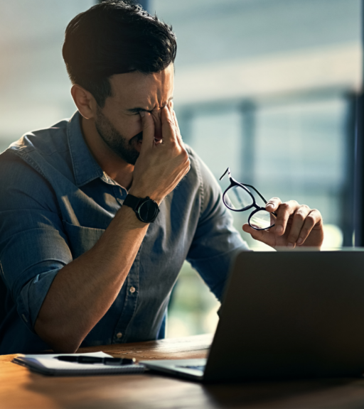 Man feeling stressed at a laptop, a common migraine trigger