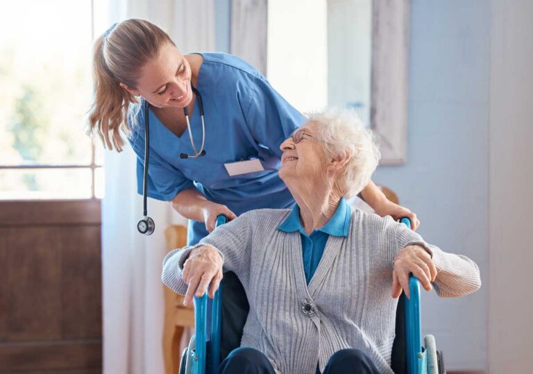 Longterm care patient in wheelchair pushed by nurse