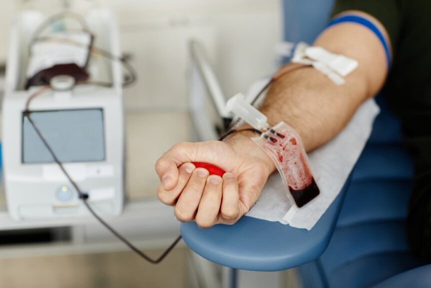 Patient receiving a blood transfusion through an IV line while resting in a clinic chair during a medical treatment procedure