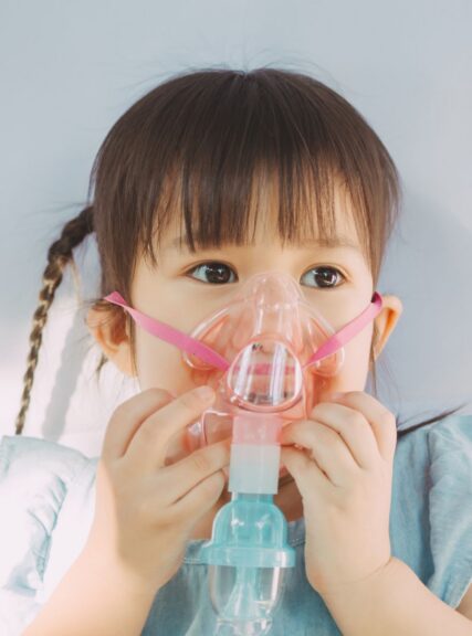 Young child wearing a nebulizer mask during respiratory treatment for asthma, breathing support, or pediatric airway care in a clinical setting