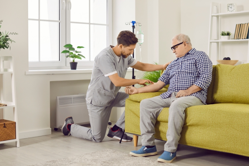 Healthcare professional providing home infusion therapy to a patient and explaining what to expect during treatment.