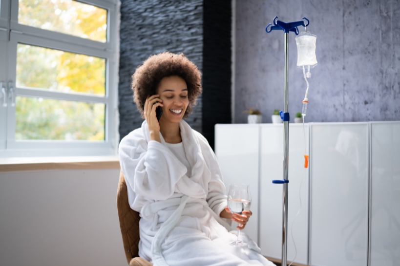 Woman relaxing during an IV iron infusion treatment with an IV drip beside her.