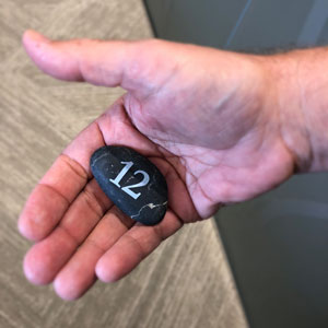Hand holding stone with a number 12 printed on it, referring to the 12 differentiating factors TwelveStone offers.
